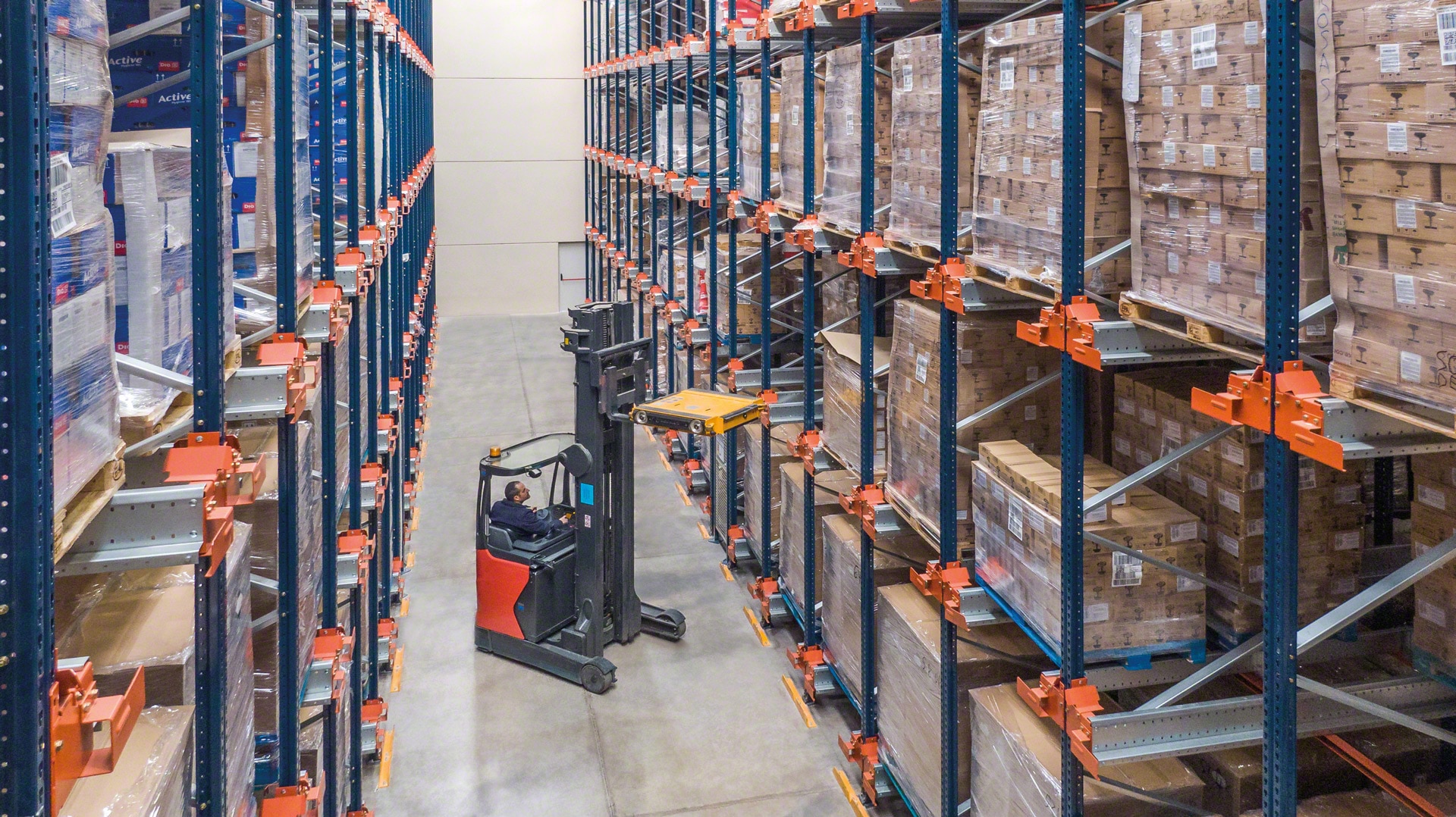 Vysokozdvižné vozíky umiestňujú vozík do skladovacieho kanála pre vkladanie a vyťahovanie tovaru v kompaktných regáloch